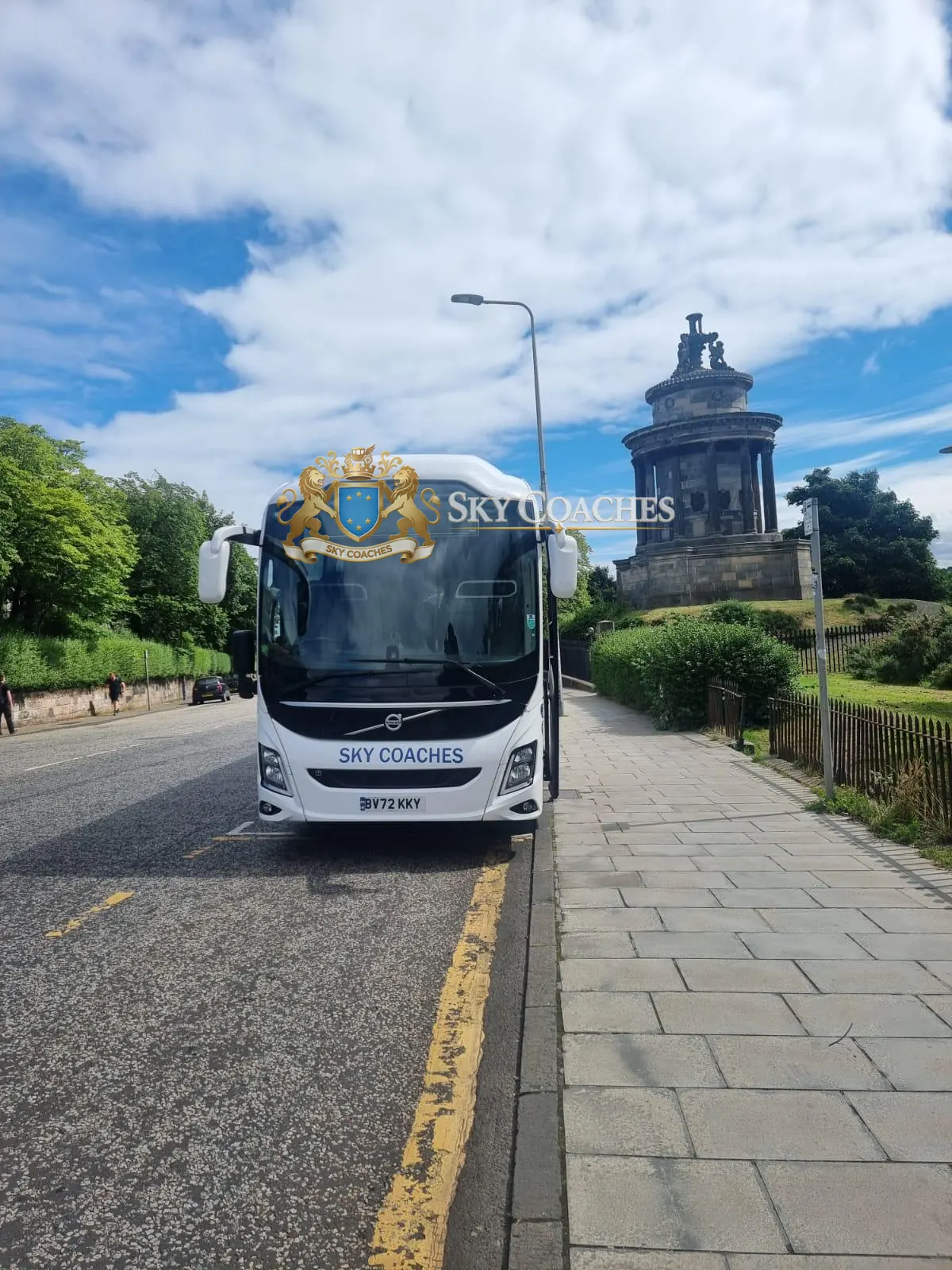 Sky Coaches Volvo coach parked beside a historic monument